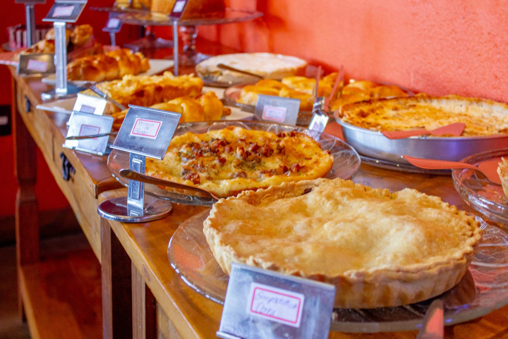 Mesa de café da manhã do Loft da Serra com tortas, pães, salgados e opções artesanais servidas em estilo buffet.